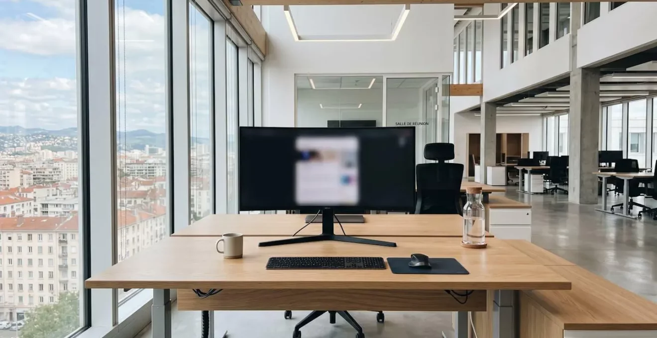 Bureau contemporain vide avec un ordinateur portable ouvert dont l'écran est totalement flouté, design minimaliste scandinave baigné de lumière naturelle